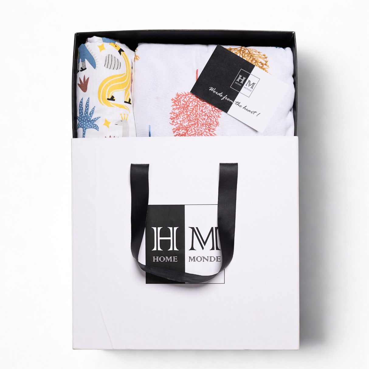 The Premium Baby & Adult Dohar Combo Set comes in a stylish white gift-ready box with black handles, featuring colorful patterned textiles and a soft cotton dohar, with contents neatly displayed and a HOME MONDE card included.