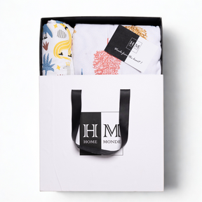 The Premium Baby & Adult Dohar Combo Set comes in a stylish white gift-ready box with black handles, featuring colorful patterned textiles and a soft cotton dohar, with contents neatly displayed and a HOME MONDE card included.