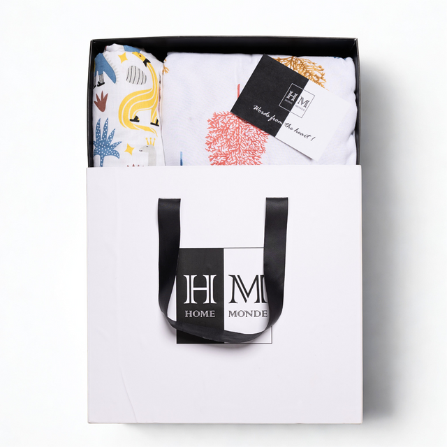 The Premium Baby & Adult Dohar Combo Set comes in a stylish white gift-ready box with black handles, featuring colorful patterned textiles and a soft cotton dohar, with contents neatly displayed and a HOME MONDE card included.
