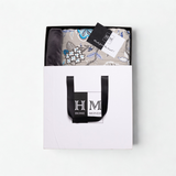 A folded Premium Dohar & Cushion Cover Combo Set in a white gift bag with black handles and the HOME MONDE logo, plus a 锟斤拷锟組ade from the heart锟斤拷锟 tag锟斤拷锟絠deal for gifting or as a stylish hom
