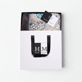 A folded Premium Dohar & Cushion Cover Combo Set in a white gift bag with black handles and the HOME MONDE logo, plus a 锟斤拷锟組ade from the heart锟斤拷锟 tag锟斤拷锟絠deal for gifting or as a stylish hom
